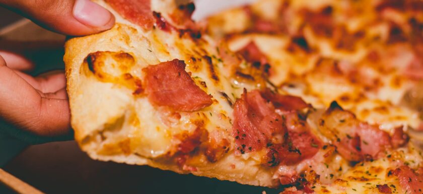 close up photo of person holding pizza