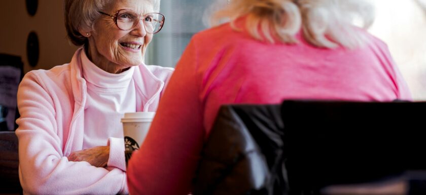 photo of old woman sitting while talking with another woman