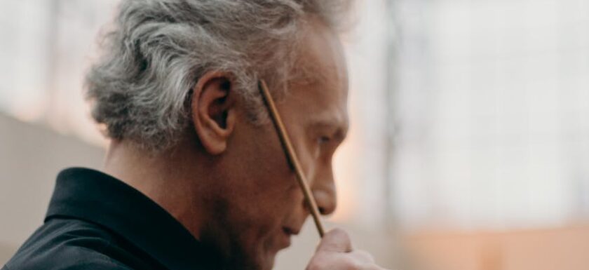 side view photo of elderly man holding a paint brush
